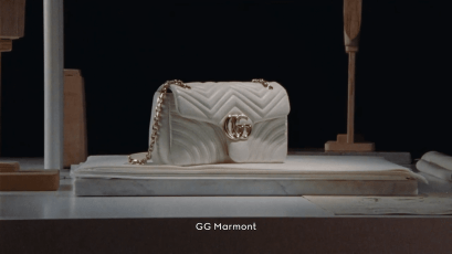 7 SEGRETI DEL MUSEO GUCCI FIRENZE: UN VIAGGIO ICONICO NEL LUSSO 20 Borsa GG Marmont di colore bianco, con dettagli in oro, esposta su un supporto elegante.
